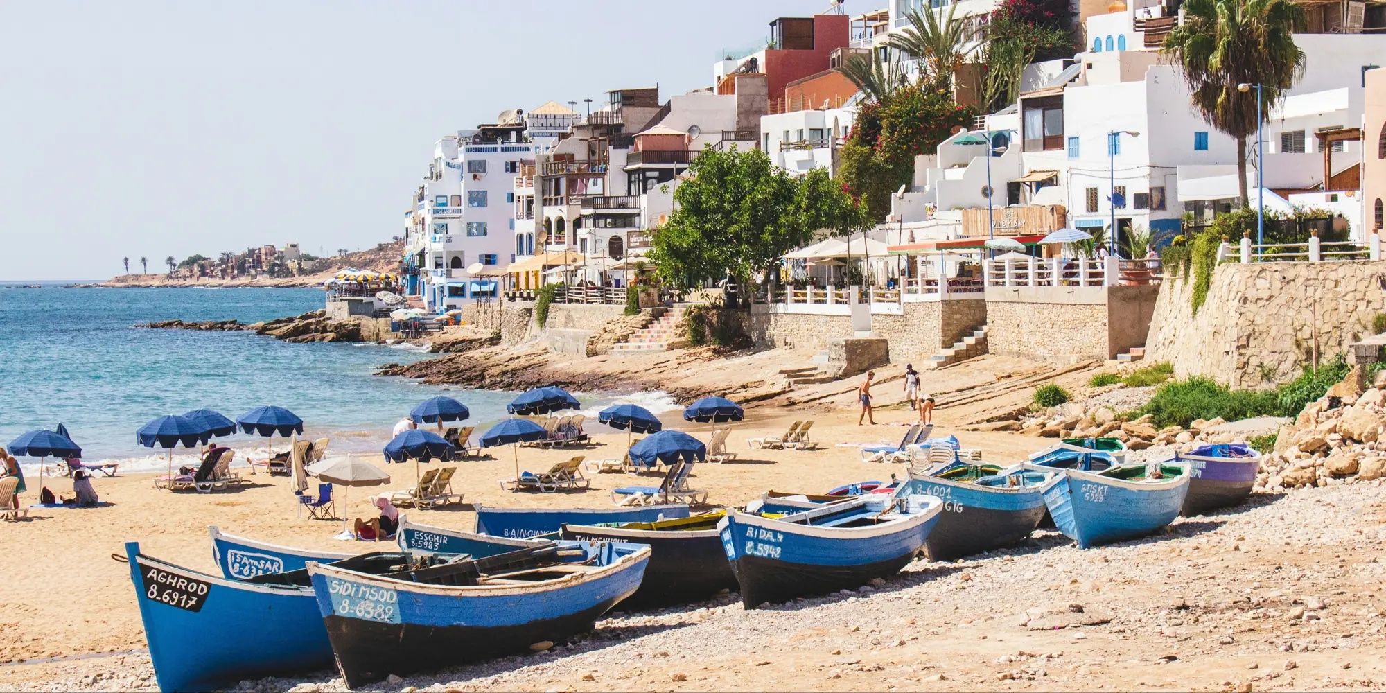Plongée avec les requins au Maroc – plage avec petits bateaux et maisons