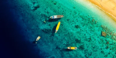 Vue aérienne de bateaux dans des eaux côtières turquoise près d’une plage de sable