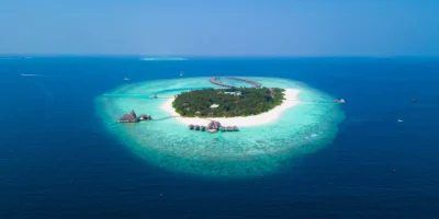 Vue aérienne d’une île boisée avec une plage blanche et un lagon turquoise aux Maldives