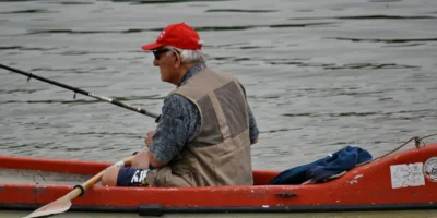 Homme avec une canne à pêche dans un kayak rouge sur l’eau