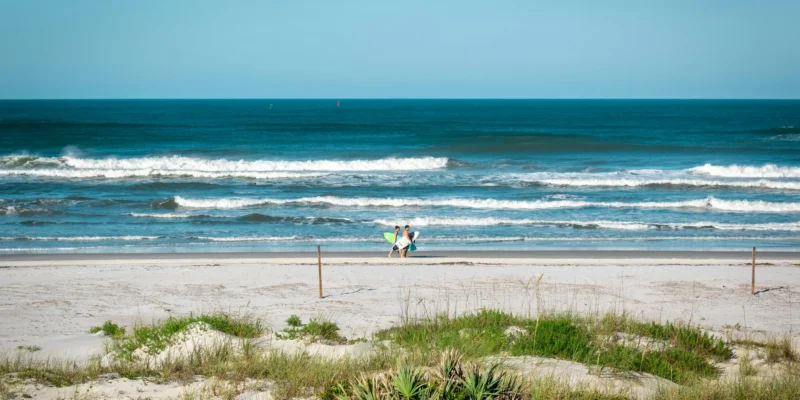 Deux personnes avec des planches de surf à New Smyrna Beach, devant les vagues