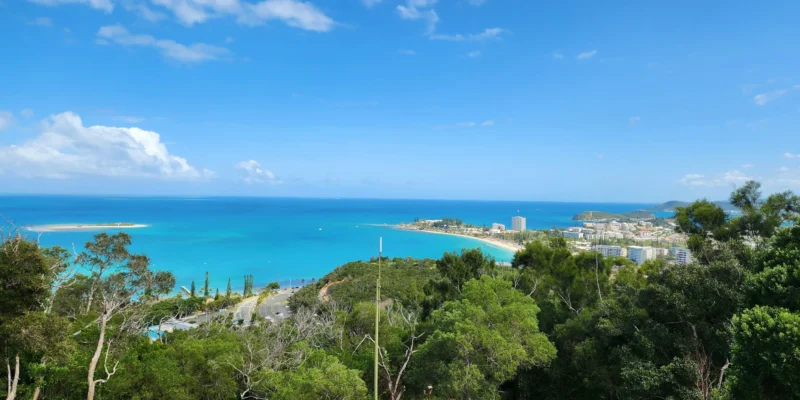 Vue depuis une colline boisée sur la baie turquoise et la ville de Nouméa