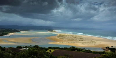 Vue sur la lagune, la plage et l’océan à Plettenberg Bay sous de sombres nuages d’orage