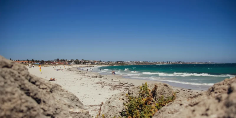Baigneurs et vagues à Sorrento Beach, avec des rochers au premier plan