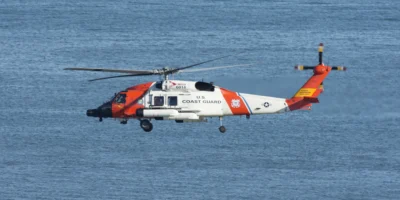Hélicoptère blanc et orange des garde-côtes américains volant au-dessus d’une mer bleue. Photo d’illustration issue des archives de 2021 ; elle ne montre pas le sauvetage au large d’Ensenada en octobre 2026.